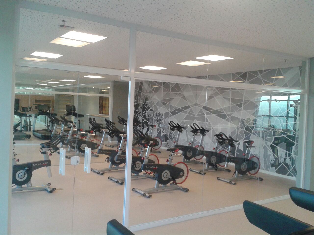Fechamento em vidro transparente em sala de bicicletas de academia.